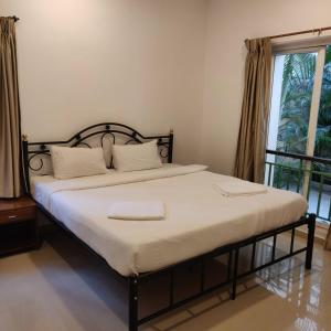 un letto in una camera con una grande finestra di Pool View Apartment - Sunshine By Leela Homes ad Arpora