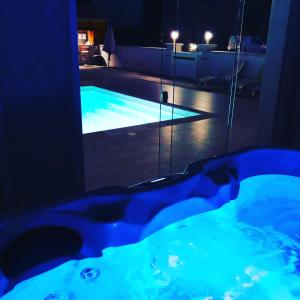 a jacuzzi tub with a view of a pool at night at Le Coteau de Bazeille Spa & Sauna in Sainte-Bazeille