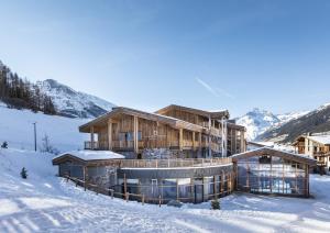 ein großes Holzgebäude im Schnee mit Bergen in der Unterkunft Les Balcons Platinium Val Cenis in Lanslevillard