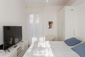 Habitación blanca con cama y TV en Amazing terrace in Milan- Città Studi en Milán