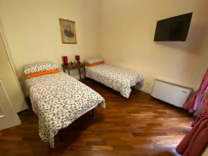 a room with two beds and a flat screen tv at La Casa di Amici Miei in Cremona