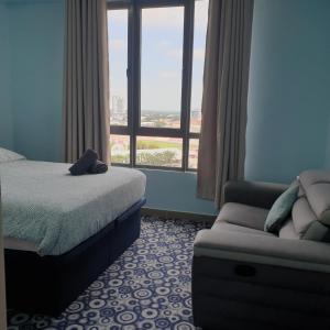 a bedroom with a bed and a couch and a window at Nice stay in heart of Kota Bharu@Troika,free Wifi. in Kota Bharu
