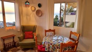 een eetkamer met een tafel, een stoel en ramen bij Casa Esperanza in Málaga
