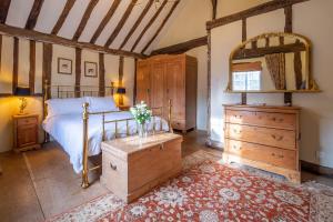 a bedroom with a bed and a dresser and a mirror at Extraordinary 15th Century timber framed cottage in famous Medieval village - The Tryst in Lavenham