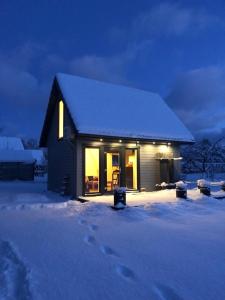 una pequeña casa en la nieve por la noche en Skrundas namiņš, en Skrunda