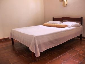 a bed with a white blanket on top of it at Hostel Universo in Ibicoara