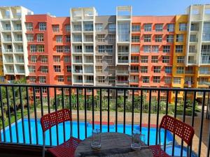 a balcony with a table and chairs and some buildings at Pool View Apartment Dabolim in Marmagao