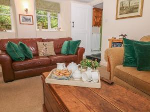 a living room with a brown leather couch and green pillows at Hope Cottage in Castleton