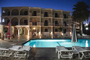 a hotel with a swimming pool in front of a building at Prokopis Studios in Laganas