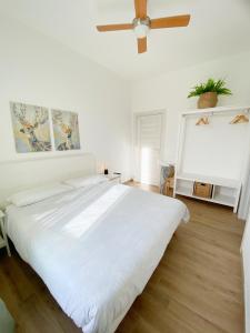 Cama blanca grande en habitación blanca con ventilador de techo en B&B La Locanda Chic, en Grosseto