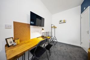 a room with a desk with a tv on the wall at 7 bedroom house ENSUITE Rooms, fully equipped kitchen, free WIFI, TVs in all rooms CITY CENTRE CLOSE TO A46 Inspire Homes in Coventry
