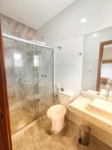 uma casa de banho com um chuveiro, um WC e um lavatório. em Pousada Villa Magna - Chalé Família em Diamantina