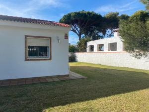 a white house with a window in a yard at Chalet Novo Sancti Petri Surf House in Chiclana de la Frontera