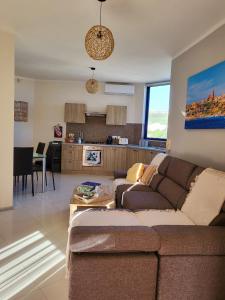 een woonkamer met een bank en een keuken bij Ir-Rixa Holiday Penthouse in Għajnsielem