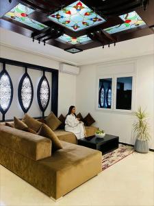 a woman sitting on a couch in a living room with a ceiling at Aparthotel & Hotel Doha in Nador