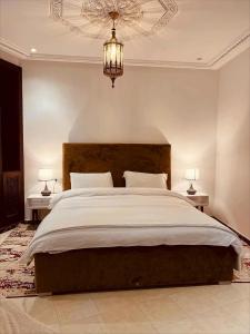 ナドールにあるAparthotel & Hotel Dohaのベッドルーム1室(大型ベッド1台、テーブル2台、シャンデリア付)