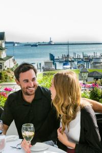 un homme et une femme assis à une table avec un verre de vin dans l'établissement Island House Hotel, à Île Mackinac