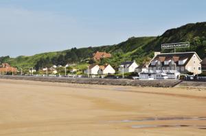 a view of a beach with houses in the background at Résidence La Plage d'Or in Vierville-sur-Mer