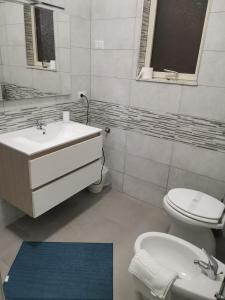 W łazience znajduje się umywalka, toaleta i lustro. w obiekcie BED&FLY NEAR AIRPORT FONTANAROSSA reception h24 w Katanii