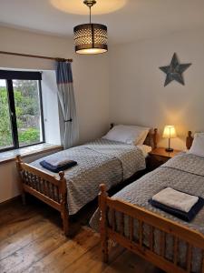 a bedroom with two beds and a window at Bowkett Cottage in Cinderford