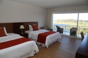 a hotel room with two beds and a large window at Altos del Arapey All Inclusive, Golf & Spa in Termas del Arapey +61 photos