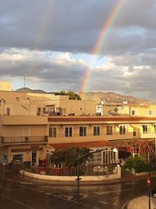 un arco iris en el cielo sobre una ciudad con edificios en Pension Cuatro Vientos, en Cuevas del Almanzora