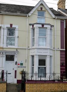 a white house with a fence in front of it at Brynhyfryd Guest House in Cardigan