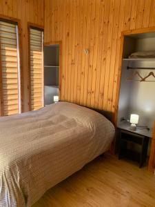 a bedroom with a bed and a wooden wall at Cabañas Los Nevados in Nevados de Chillan