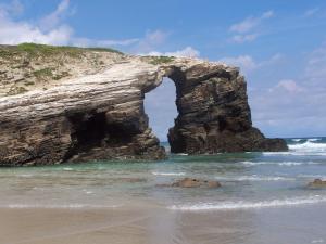 an arch in the rocks on the beach at Hotel San Briz in A Pontenova