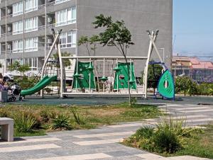 a playground with a green slide in a park at Hermoso departamento con piscina, muy cerca del centro, playas, malls, hipermercado, hospital y clínicas in La Serena