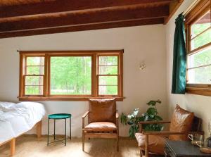 a bedroom with a bed and a chair and windows at The Lorca Adirondacks Motel in Indian Lake