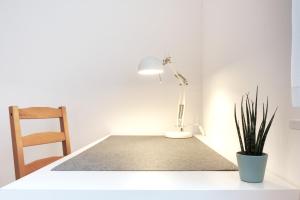 einen Schreibtisch mit einer Lampe und einer Topfpflanze in der Unterkunft Schicke & helle Wohnung in Mülheim an der Ruhr in Mülheim an der Ruhr