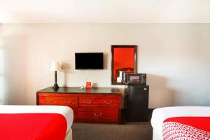 une chambre d'hôtel avec un lit et une commode avec une télévision dans l'établissement OYO Hotel Texarkana North Heights AR Hwy I-30, à Texarkana