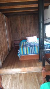 Casa los Lobos a una cuadra de la playa El Quisco في كيسكو: غرفة نوم بسرير في غرفة ذات أرضيات خشبية