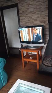 Casa los Lobos a una cuadra de la playa El Quisco في كيسكو: تلفزيون بشاشة مسطحة جالس على طاولة في غرفة المعيشة