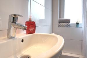 zlew w łazience z czerwoną butelką mydła w obiekcie Schicke & helle Wohnung in Mülheim an der Ruhr w mieście Mülheim an der Ruhr