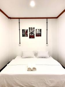 a bedroom with a white bed with three pictures on the wall at Hiraeth island home in Guraidhoo