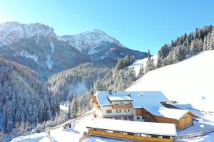 a building on a snowy mountain with mountains in the background at ALMRESIDENZ UNTERRAIN -1 km BY CAR DISTANCE SKI SLOPES KRONPLATZ in Valdaora