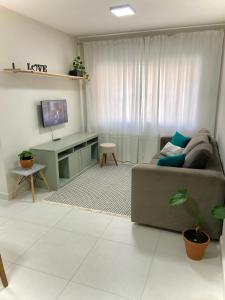 a living room with a couch and a tv at Apartamento no centro, ar-condicionado e garagem in Criciúma +4 photos
