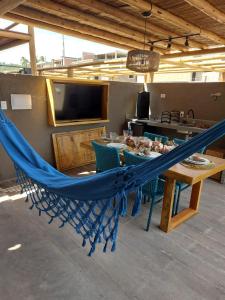 a blue hammock in a living room with a table and chairs at Casa Riacho in São Miguel dos Milagres