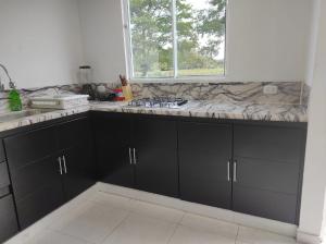 a kitchen with black cabinets and a marble counter top at Villas Campestres las Heliconias - Villa Ginger in Villavicencio