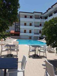 a pool with tables and chairs in front of a building at Elijah Hotel in Kemer