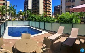 um pátio com uma mesa e cadeiras e uma piscina em Vacanze - Golden Place em Maceió