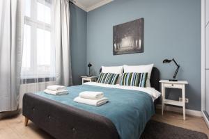 a blue bedroom with a bed with towels on it at City of the Kings - Mosaic Apartment in Krakow