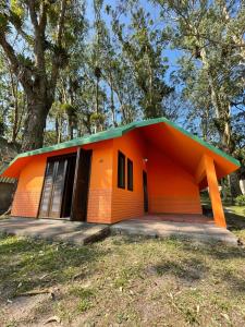 una pequeña casa naranja con techo verde en Chalé Morro dos Conventos, en Araranguá