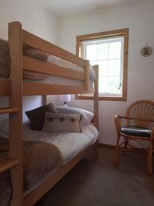 1 dormitorio con litera, silla y ventana en Pine Cabin, Strathyre. A cosy escape from it all. en Strathyre