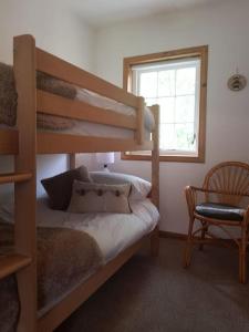 a bedroom with a bunk bed and a chair and a window at Pine Cabin, Strathyre. A cosy escape from it all. in Strathyre