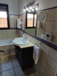 ein Badezimmer mit Waschbecken, Spiegel und Badewanne in der Unterkunft Casa Juanse in Conil de la Frontera