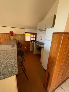 a kitchen with a white refrigerator and a counter top at Chalé Morro dos Conventos in Araranguá