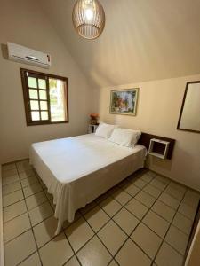 um quarto com uma grande cama branca num quarto em Chalé Morro dos Conventos em Araranguá